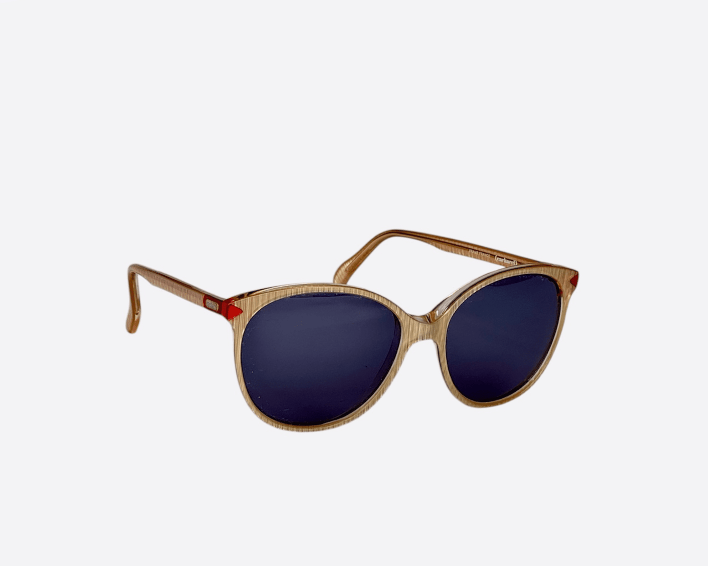 Side view of pre-loved 1980s Cacharel sunglasses with beige frames and new grey lenses, showing the visible Cacharel logo on the temples.