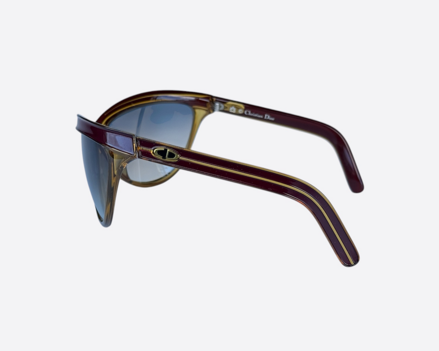 Close-up of the Christian Dior Sport logo on model 2205 sunglasses, made in Germany, featuring a dark red and yellow frame and new grey gradient lenses, highlighting the branding, optyl material and sporty frame details.