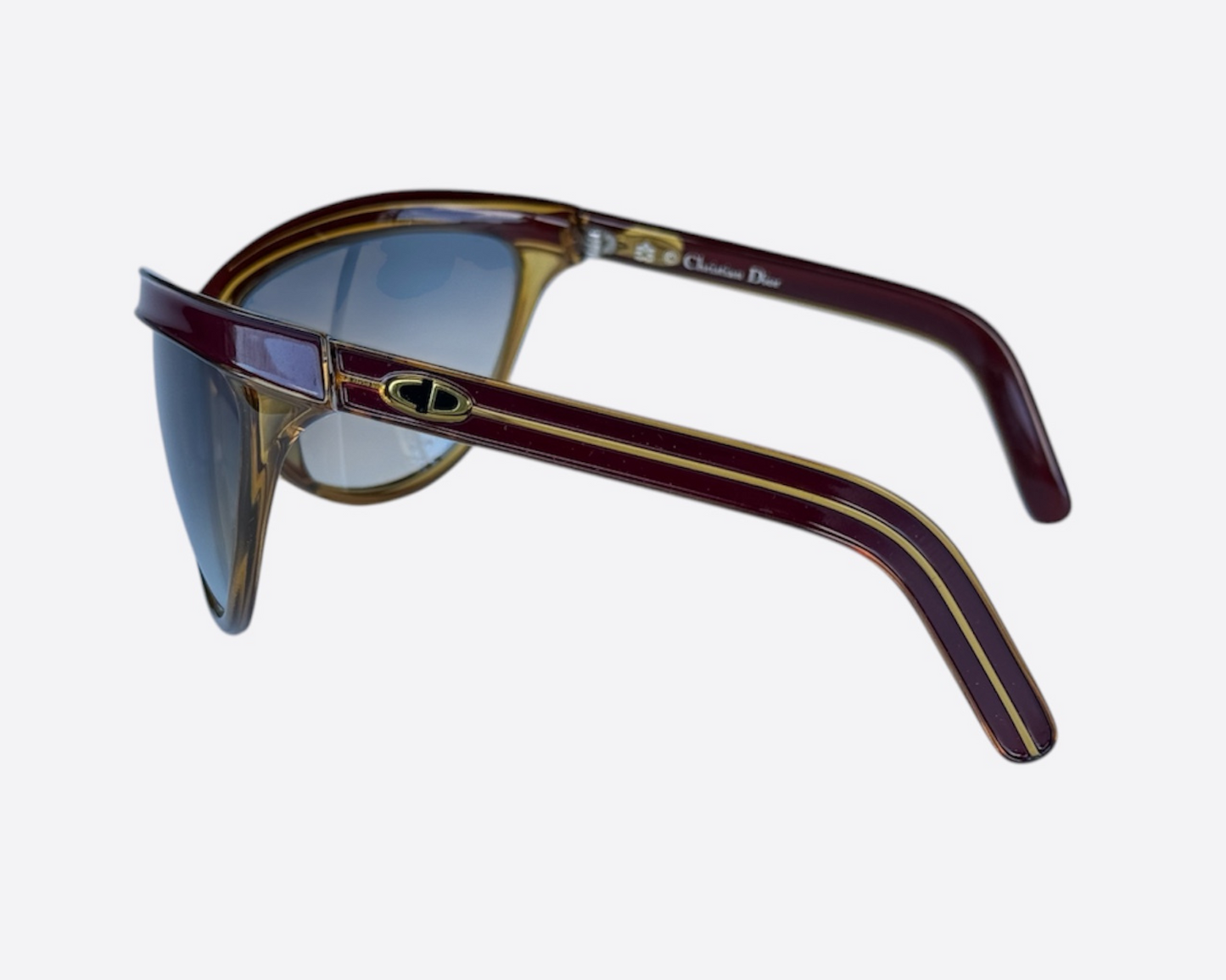 Close-up of the Christian Dior Sport logo on model 2205 sunglasses, made in Germany, featuring a dark red and yellow frame and new grey gradient lenses, highlighting the branding, optyl material and sporty frame details.