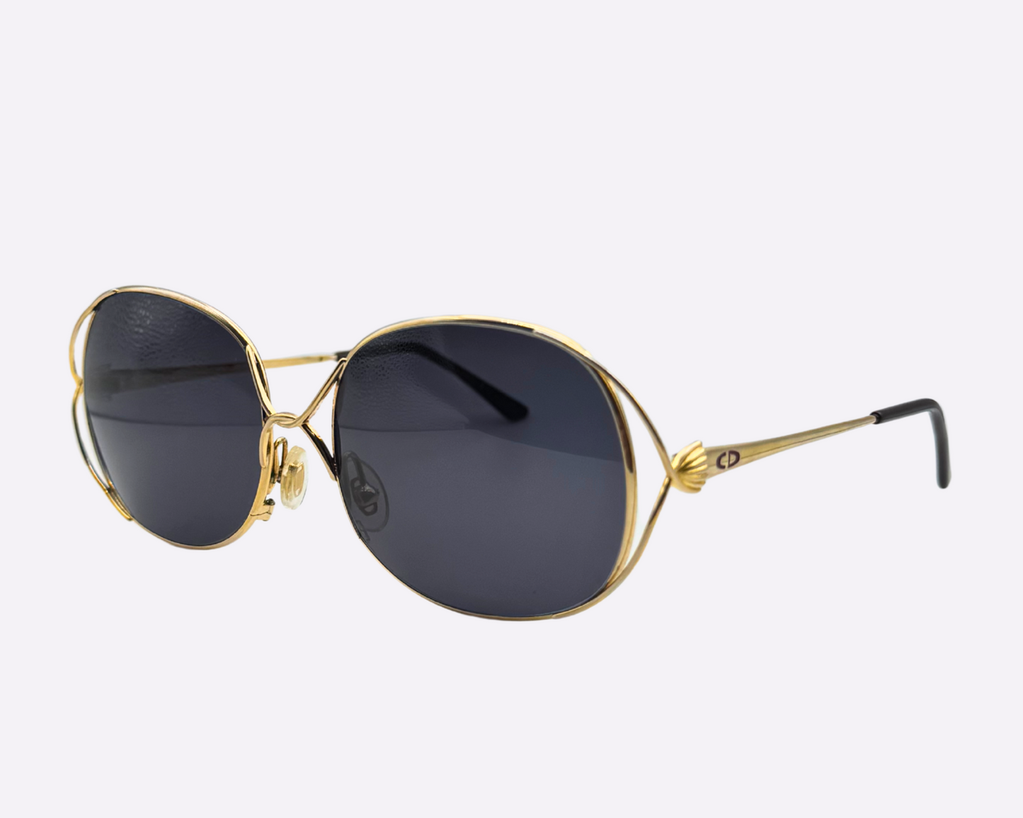 Side view of vintage 1980s Christian Dior sunglasses featuring a steel frame and new grey lenses, shown on a light gray background.