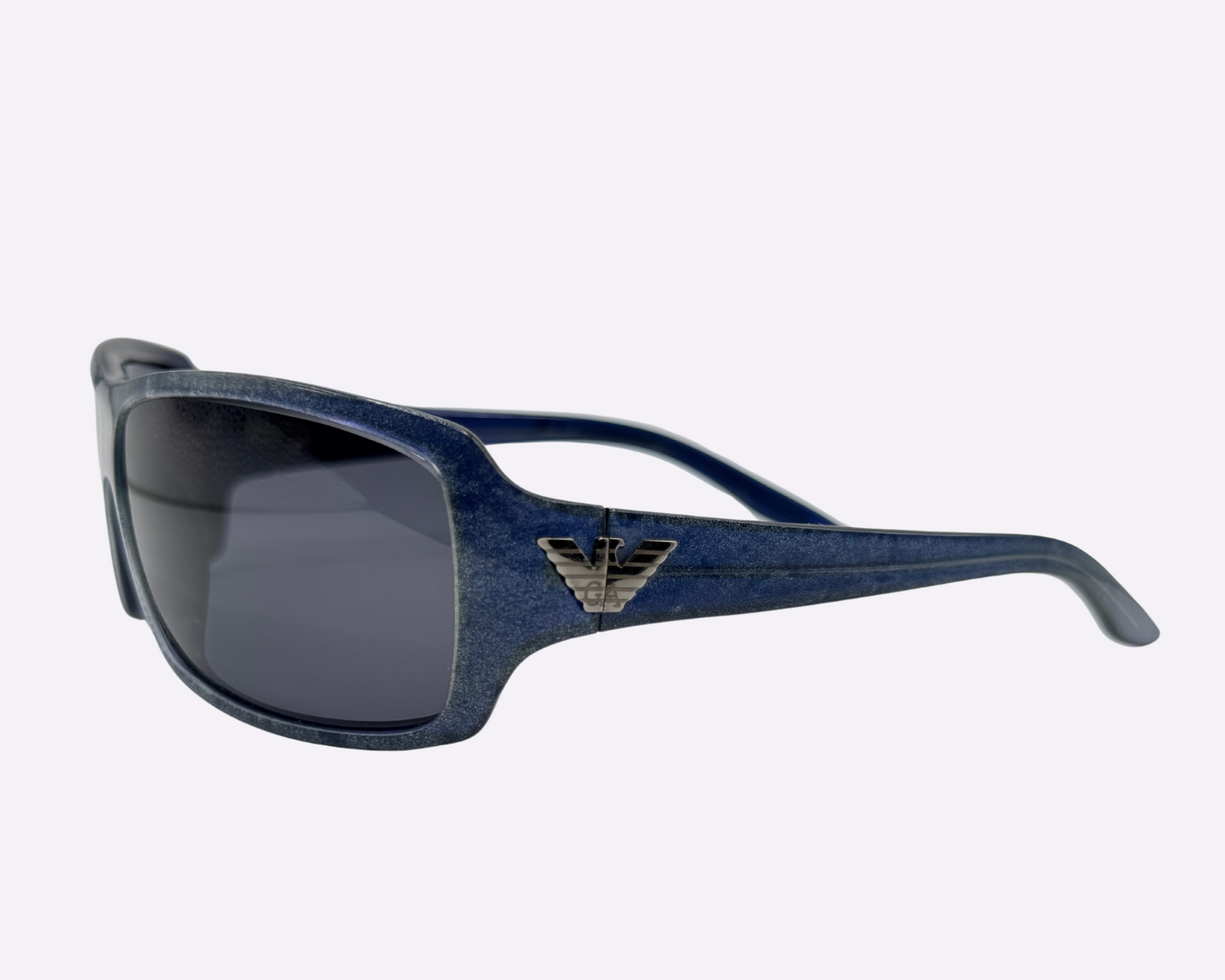 Side view of early 2000s Armani sunglasses made in Italy, showing the dark blue speckled frame, new grey lenses, and Armani logo on the temple, shown on a light gray background.
