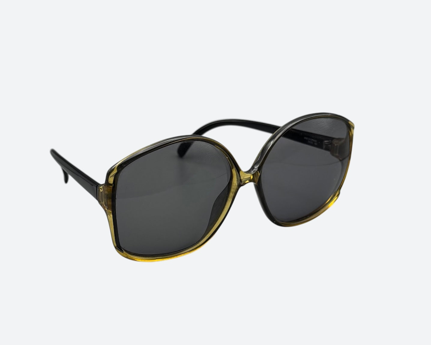 A pair of vintage Optyl sunglasses with a green tinted frame and dark lenses, crafted in Germany in the 70s or 80s.