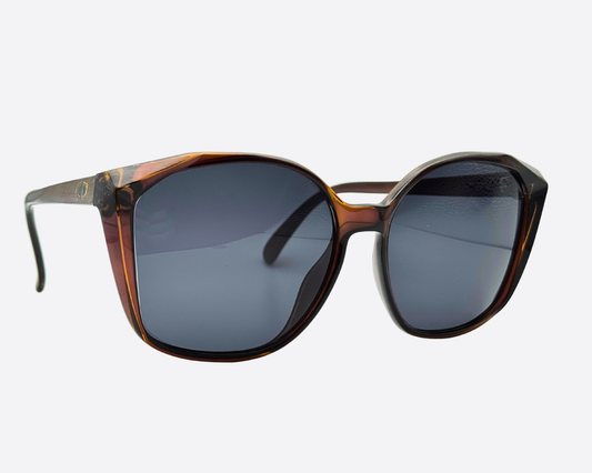 Angled front view of the 70s Dior 2232 sunglasses. Highlights the faceted edges on the brown tortoiseshell frame and the dark grey lenses.