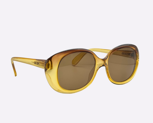 Side view of vintage 1980s Terri Brogan sunglasses, model 8752 80, with thick gold optyl frames, shown on a light gray background.