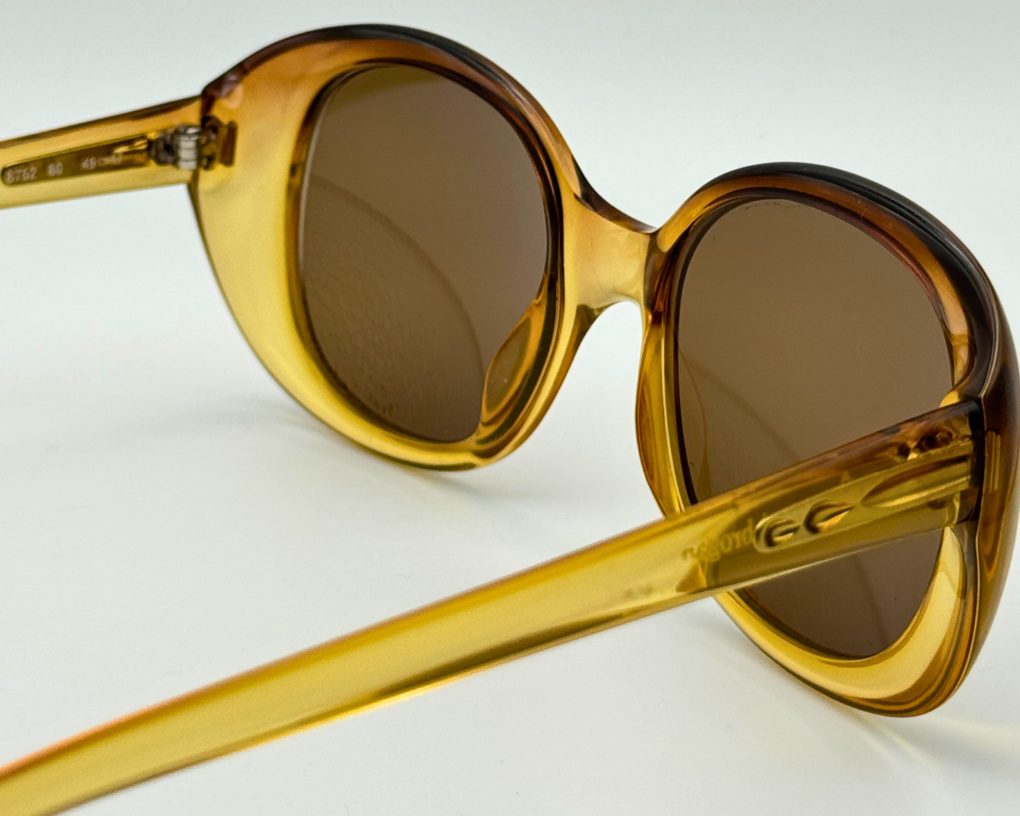 Close-up of the temple on vintage 1980s Terri Brogan sunglasses, model 8752 80, with thick gold optyl frames and new brown lenses, shown on a light gray background.