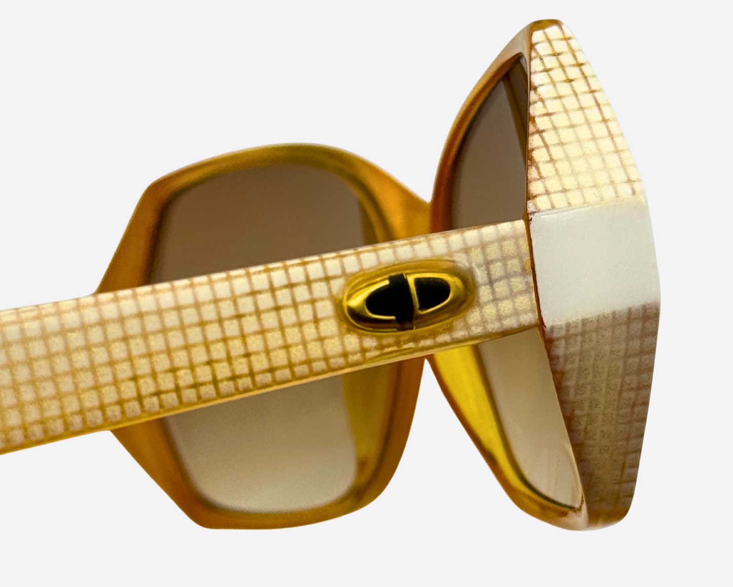 Close-up showing the metallic oval Dior logo detail on the patterned gold temple of the 80s sunglasses.