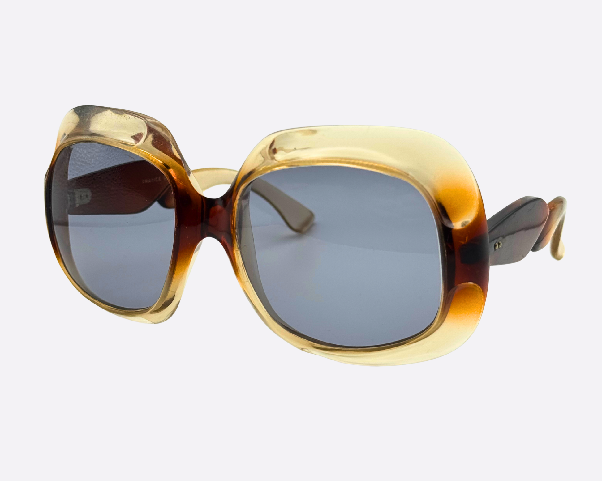 Side view of 70s French couture sunglasses showing the thick sculptural acetate temples with a translucent honey and brown two-tone finish.