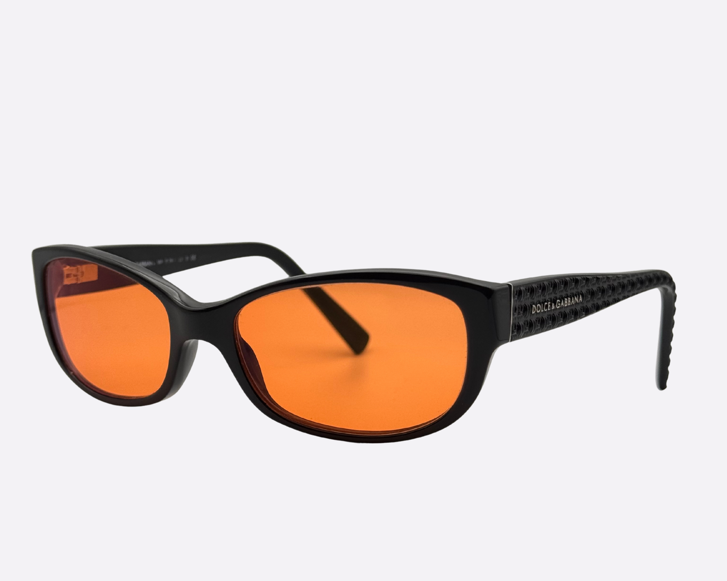 Angled right side view of the Dolce & Gabbana DG3125 sunglasses. Focuses on the shiny black frame and the vibrant new orange lenses.