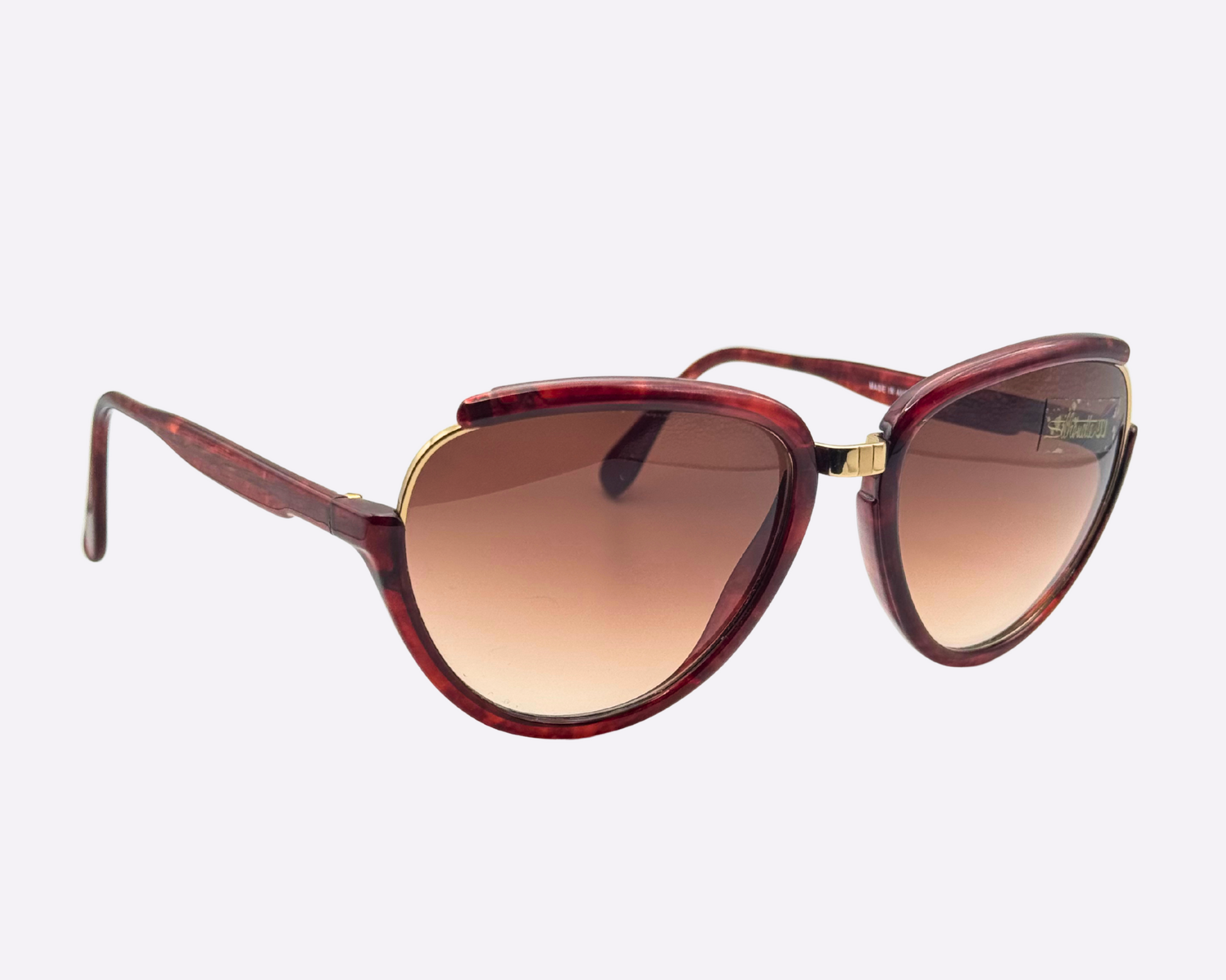 Side view of vintage 1980s Silhouette M8023/20 cat-eye sunglasses featuring a gold and tortoise frame made of optyl and metal, with original brown gradient lenses, shown on a light gray background.