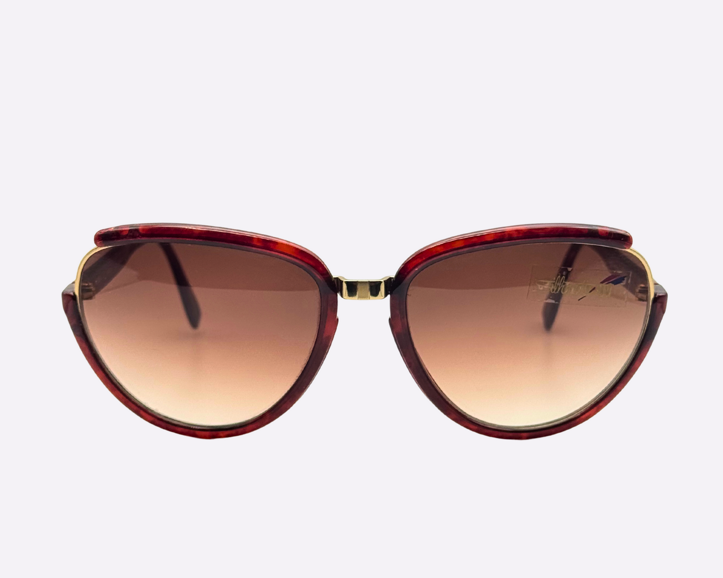 Front view of vintage 1980s Silhouette M8023/20 cat-eye sunglasses with gold and tortoise optyl and metal frame and original brown gradient lenses, shown on a light gray background.