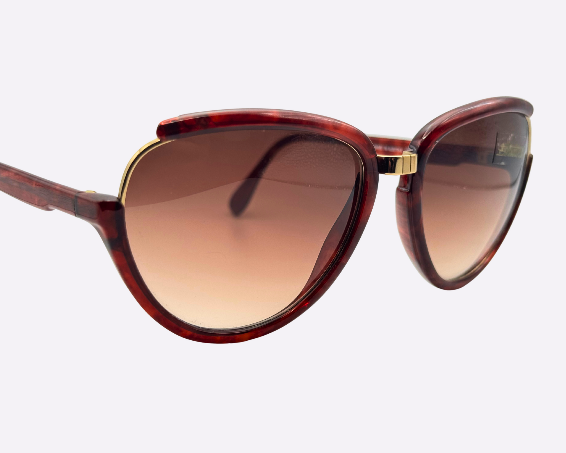 Close-up of vintage 1980s Silhouette M8023/20 cat-eye sunglasses with a gold and tortoise optyl and metal frame and original brown gradient lenses.