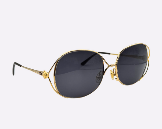 Side view of vintage 1980s Christian Dior sunglasses featuring a steel frame and new grey lenses, shown on a light gray background.