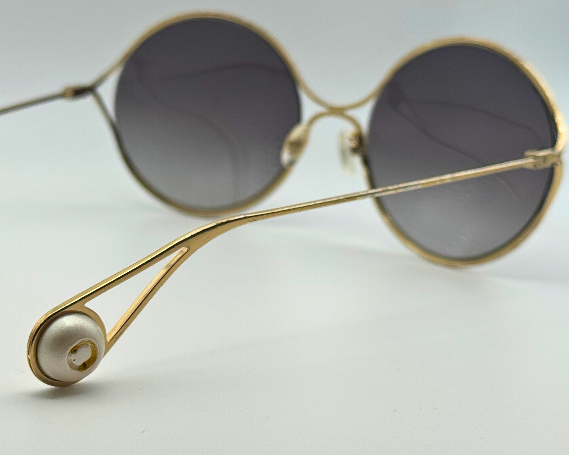 Gold-framed Gucci sunglasses with dark lenses on a light gray background