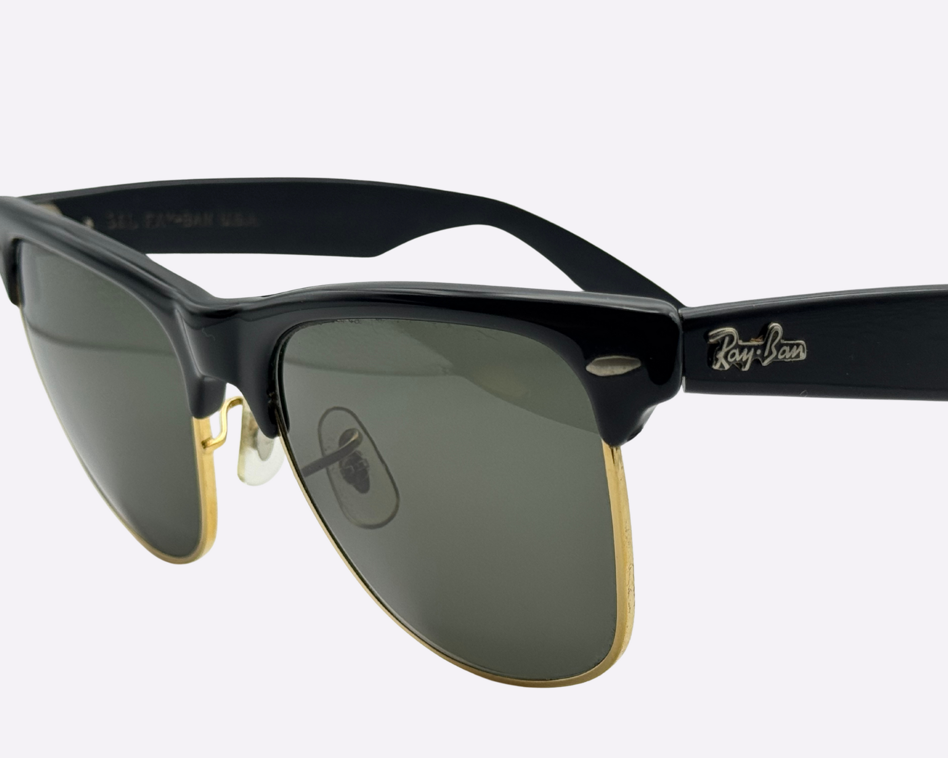 Close-up of the green G-15 lenses and Ray-Ban logo on the temple of vintage 1980s Wayfarer Max sunglasses on a white background.