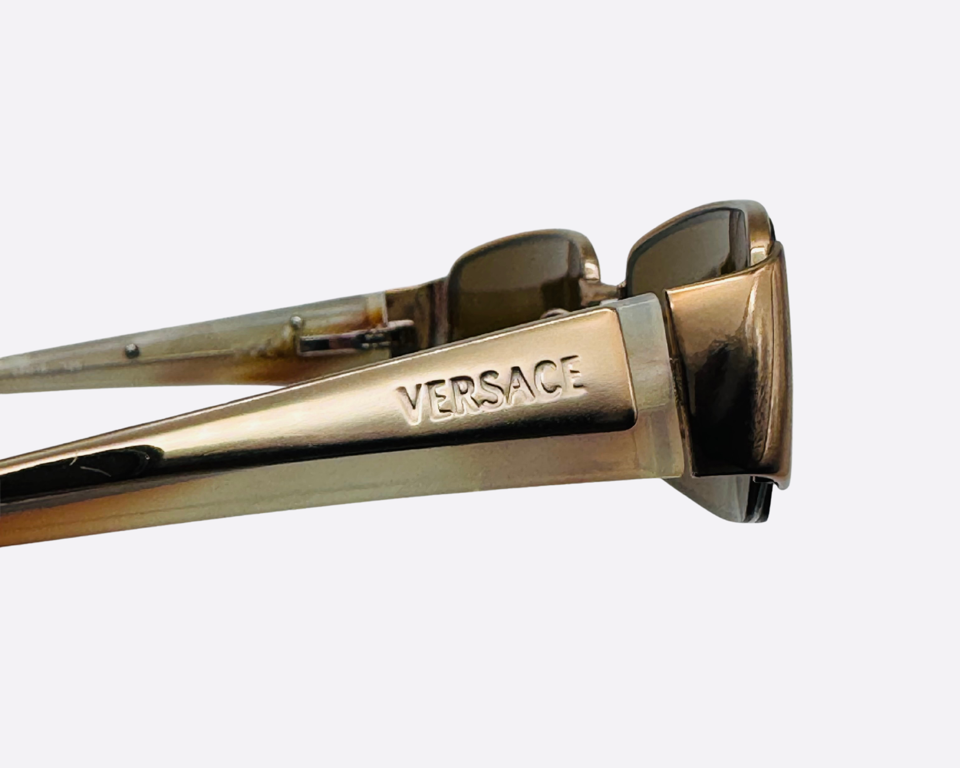Close-up of the Versace brand name engraved on the metallic bronze temple.