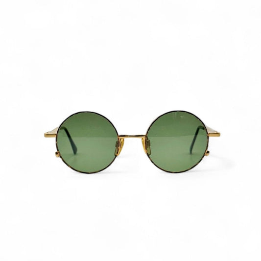 Front view of vintage 90s sunglasses with green lenses, gold frames, and a subtle brown speckled pattern around the edges. These OLIVER by Valentino are made in Italy, the sunglasses showcase a blend of retro and modern style.