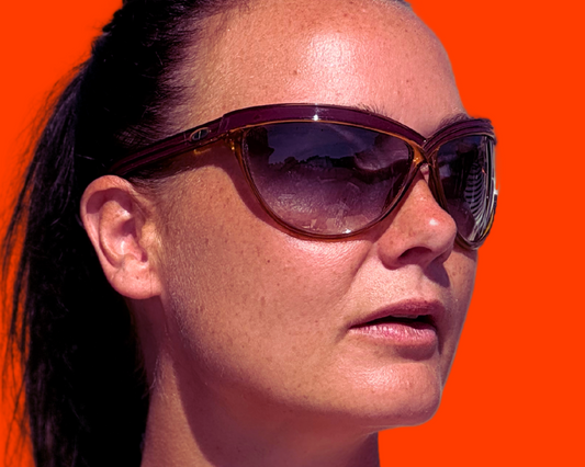 Woman wearing dior sunglasses with a red/orange background